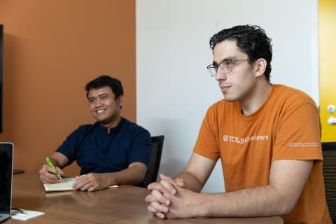 two students sitting in an office talking and smiling