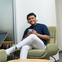 student sitting and smiling with headphones on