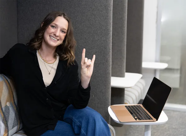 student with hook em horns symbol